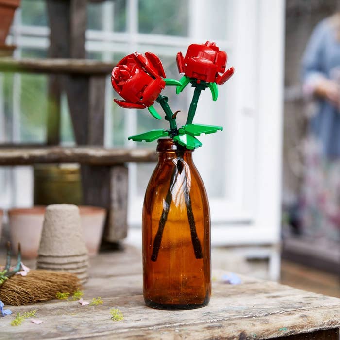 Lego flowers in a bottle on a wooden surface