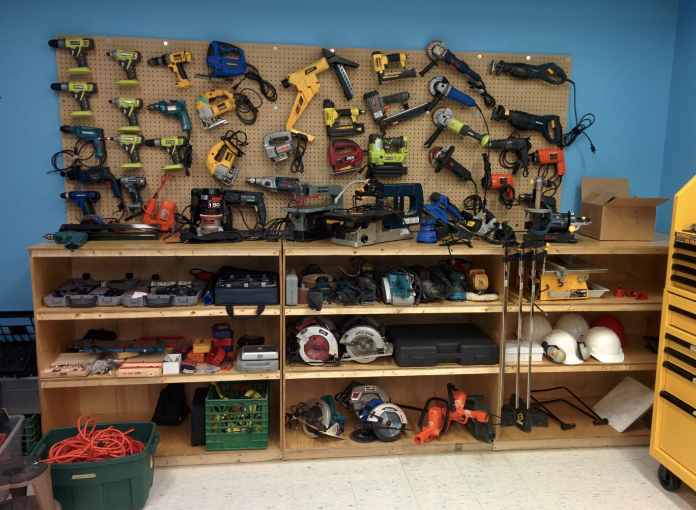 A wall and shelves in a workshop with various power tools and equipment neatly organized
