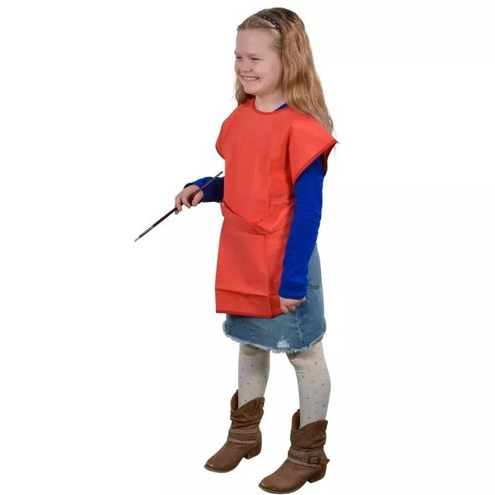 child in a faux superhero costume with cape, denim skirt, and brown boots
