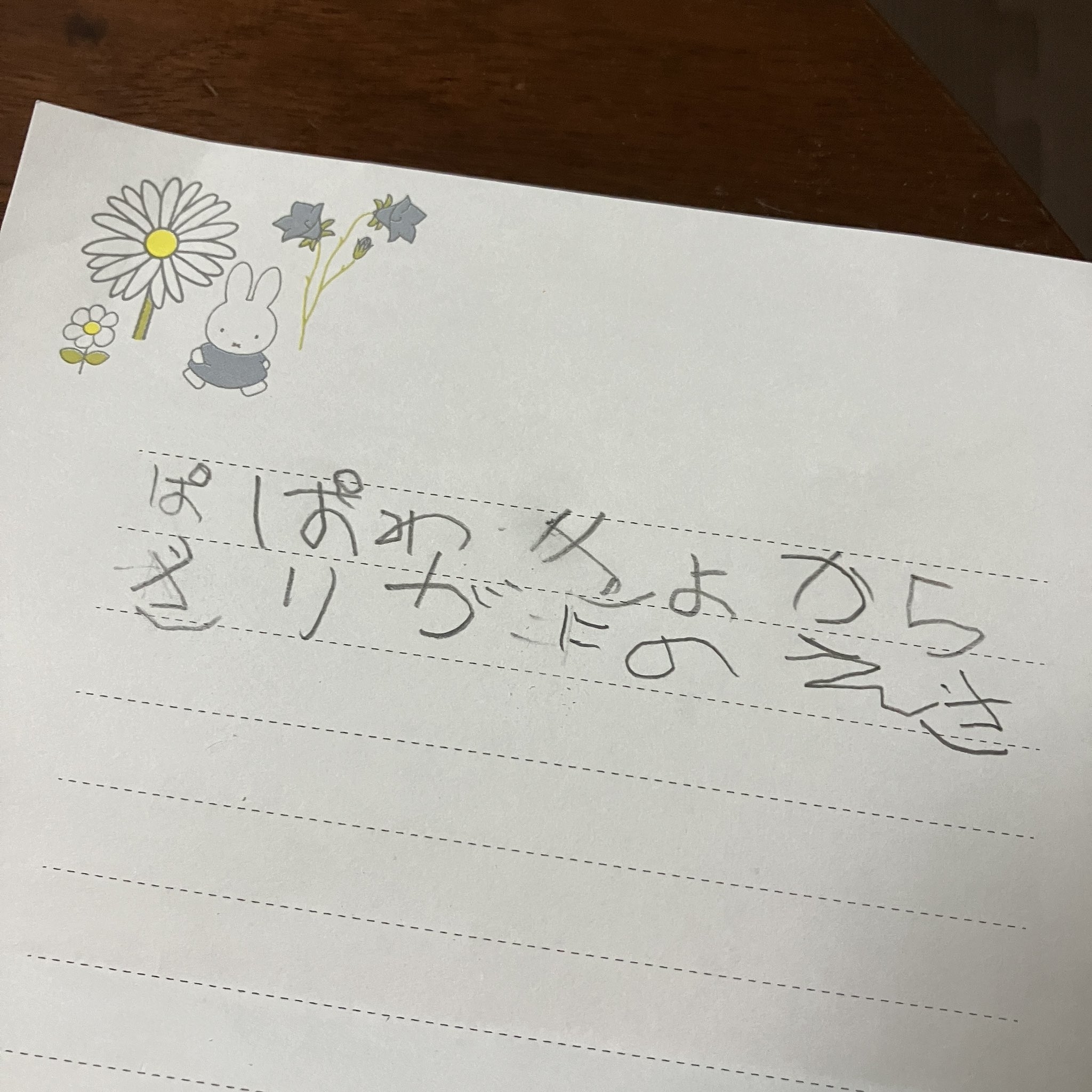 子供の手書き文字と絵が描かれた紙。&quot;Miffy&quot;キャラクターと花が描かれている。