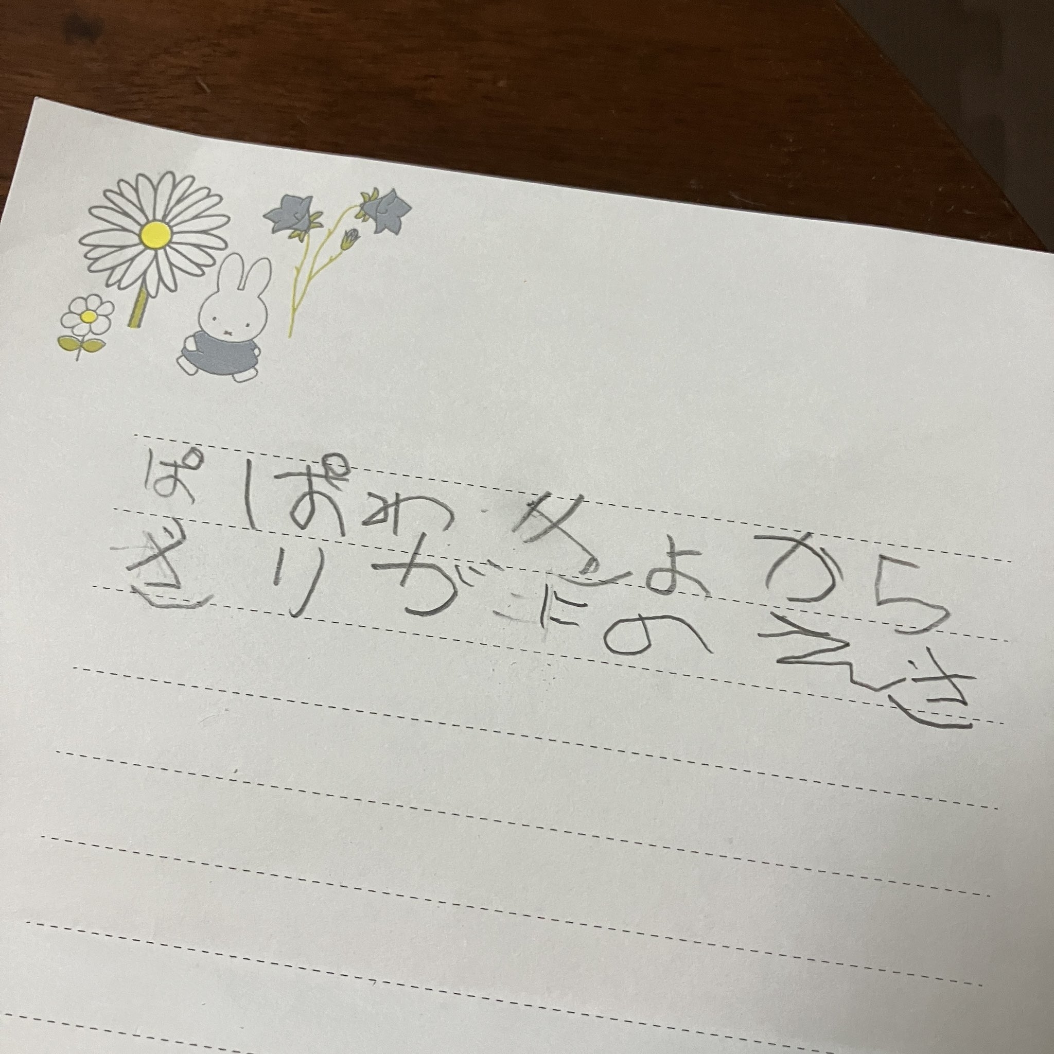 子供の手書き文字と絵が描かれた紙。"Miffy"キャラクターと花が描かれている。
