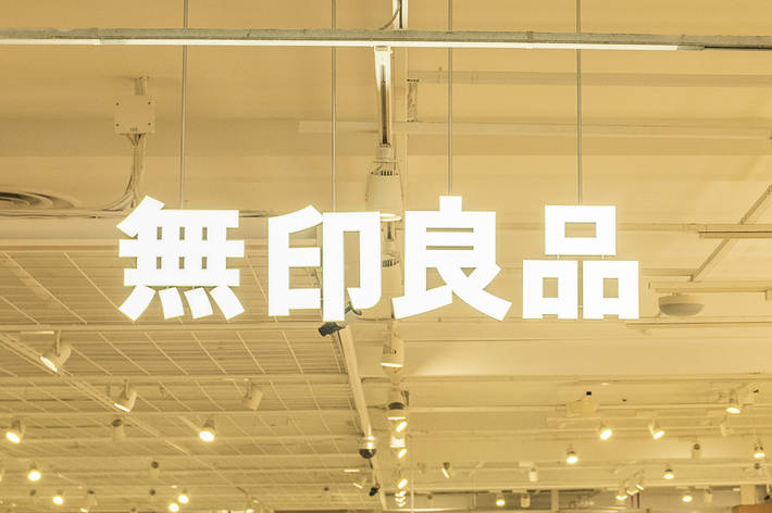 店内照明の下、商品が並ぶ店舗内部と買い物客。