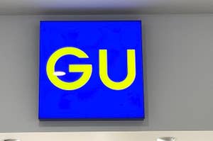 A blue sign with the letters 'GU' mounted on a wall