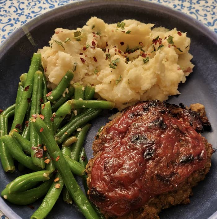 A plated meal with meatloaf, green beans, and mashed potatoes
