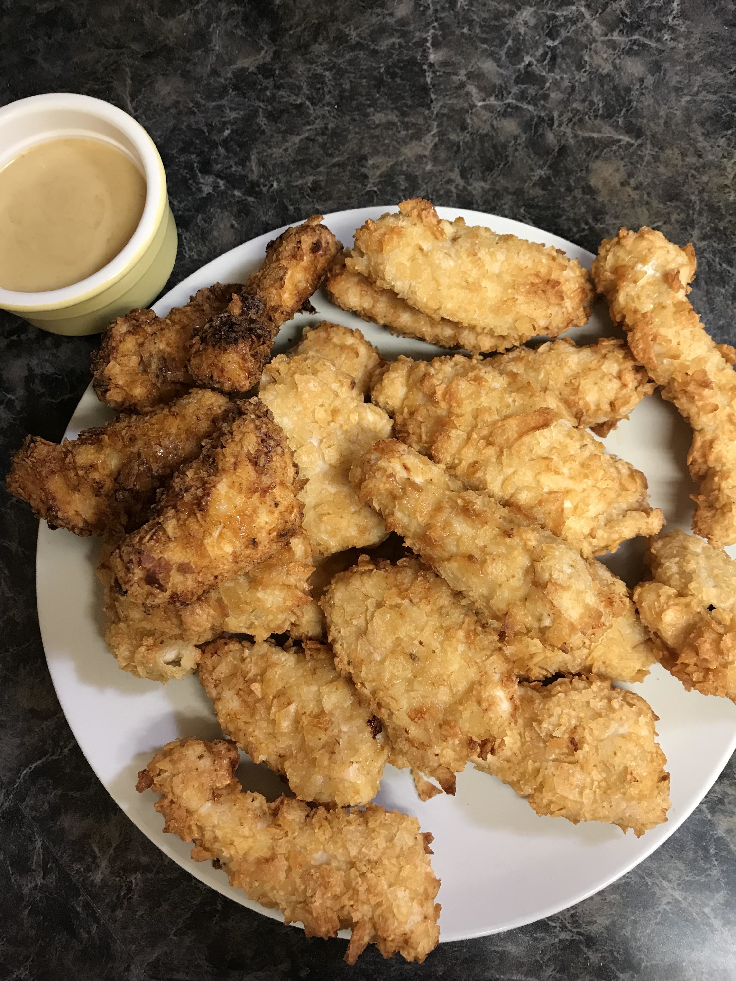 Plate of breaded chicken tenders with a side of dipping sauce