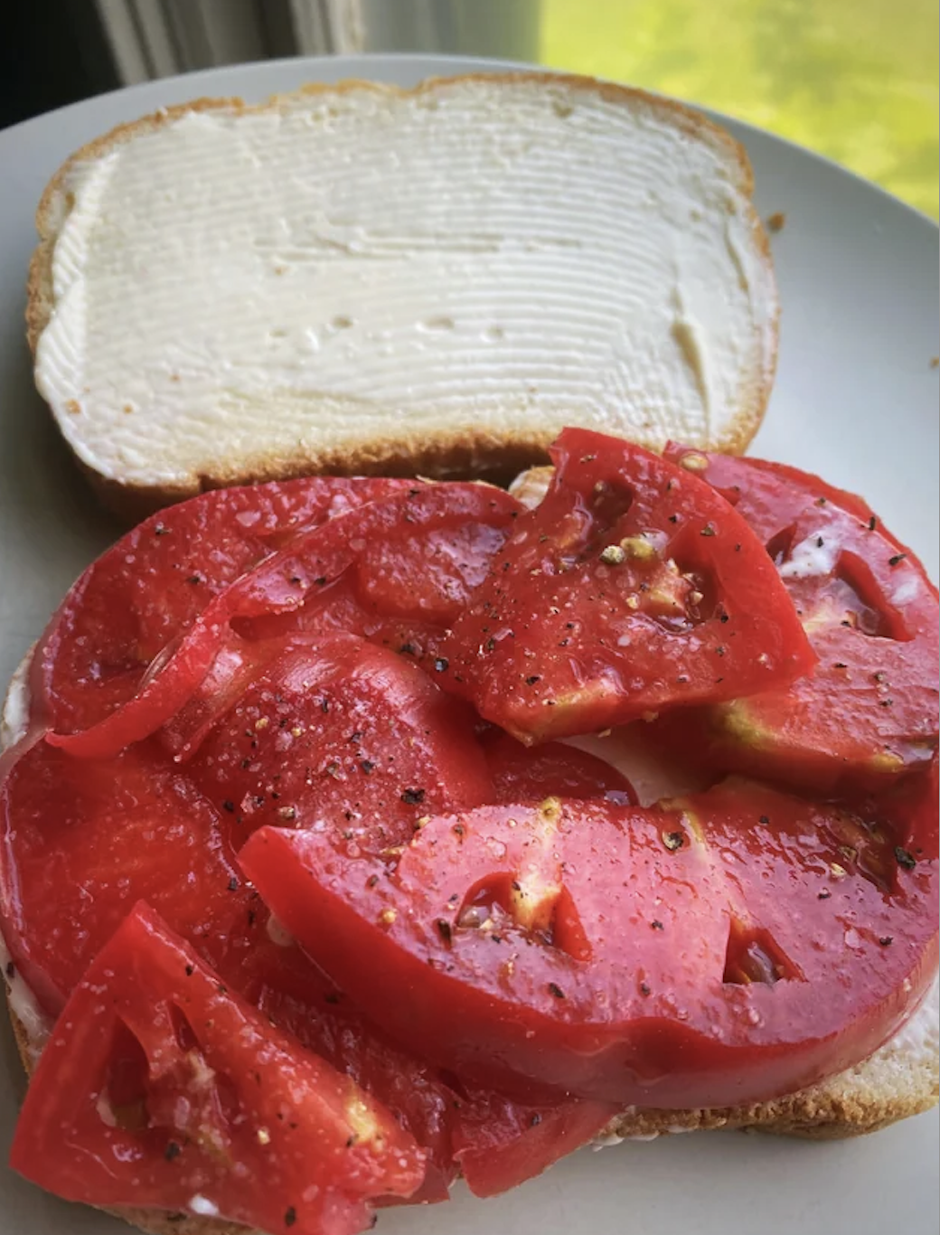 Open sandwich with a layer of cream cheese and sliced tomatoes on top
