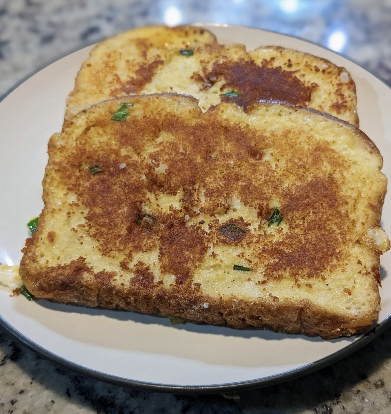 Two slices of French toast on a plate, garnished with herbs