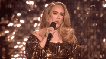 Adele performs onstage in a sparkling long-sleeve dress