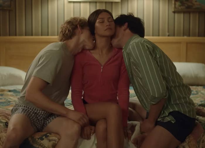 The image is a still from the &quot;Challengers&quot; movie trailer showing three people in a close moment on a bed, likely from a scene in the film