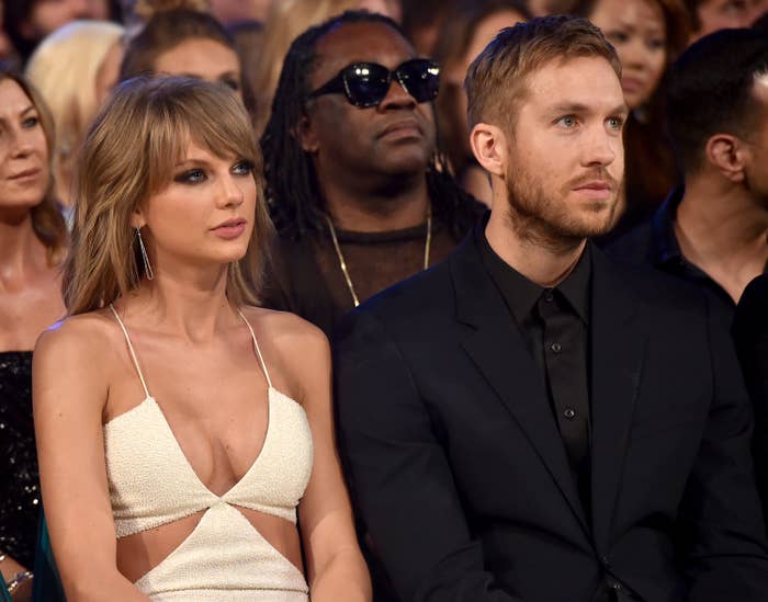 Taylor Swift in a low-cut top and Calvin Harris in a black suit seated at an event