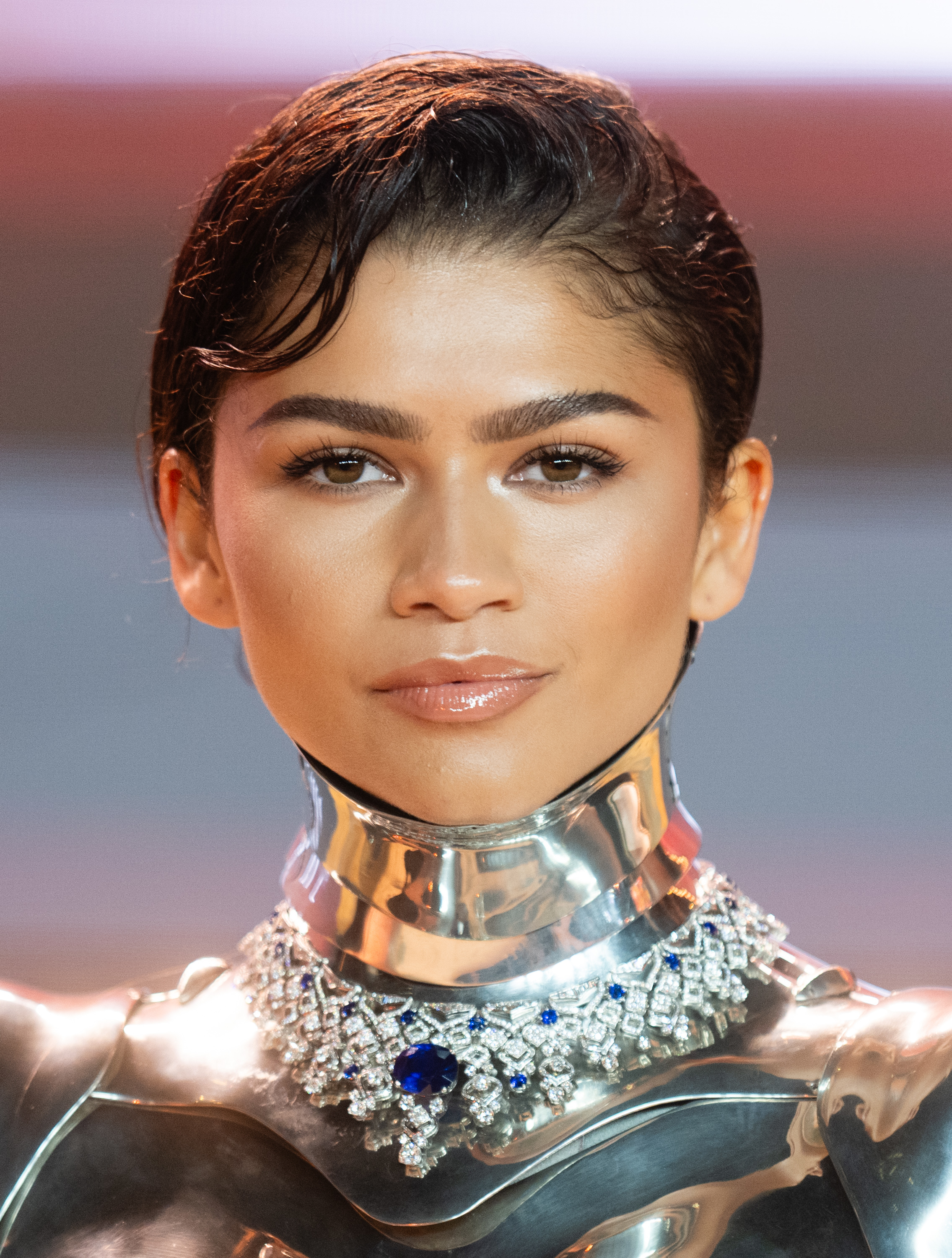 Close-up of Zendaya in a metallic outfit with a prominent jeweled necklace