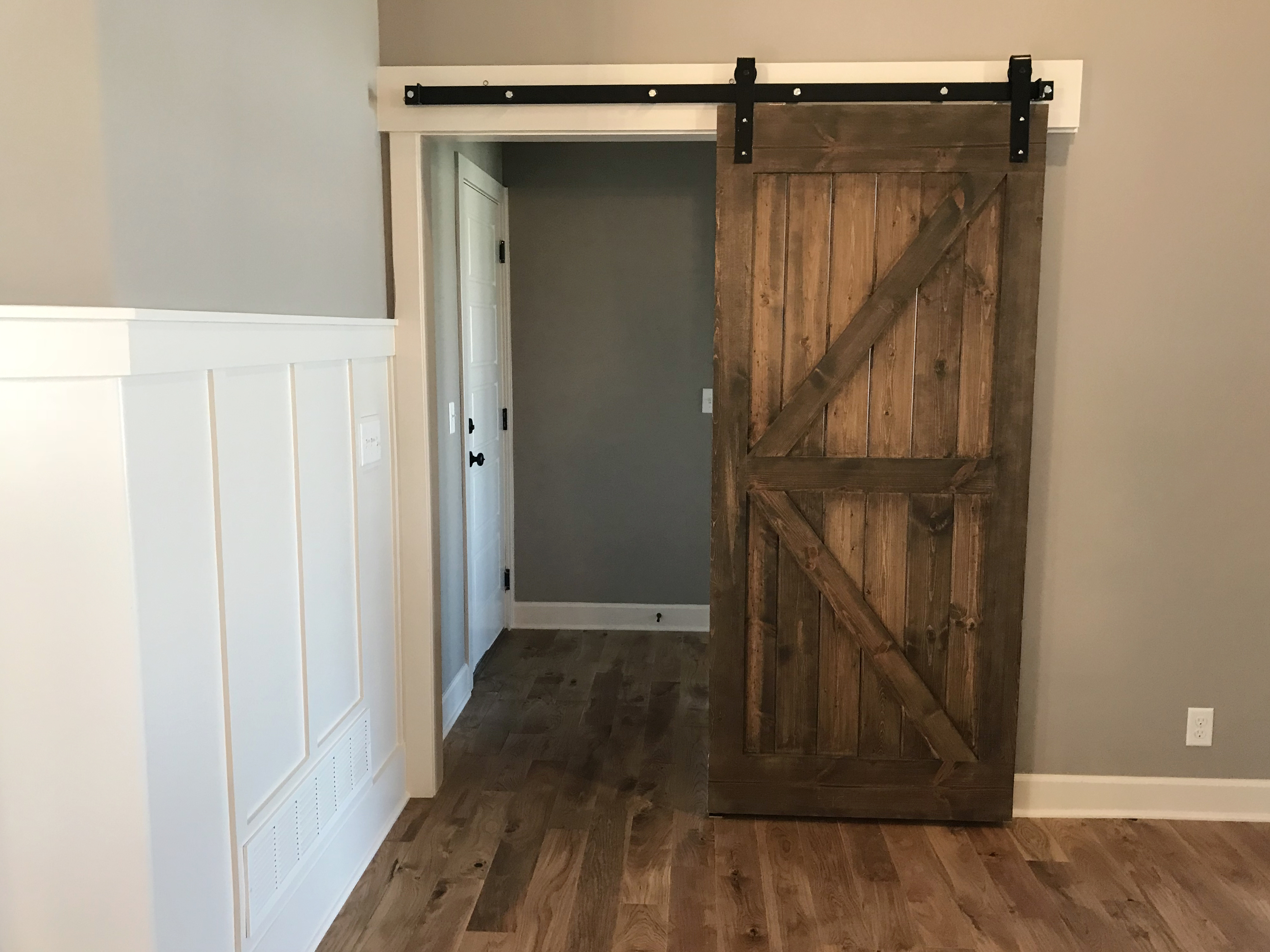 Sliding barn door in a modern home interior, partially open to reveal an adjoining room
