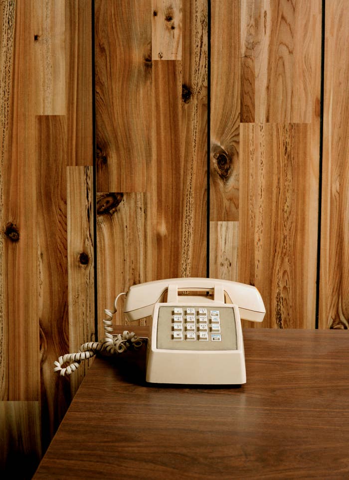 Vintage-style beige telephone on a polished wood surface against a wooden wall