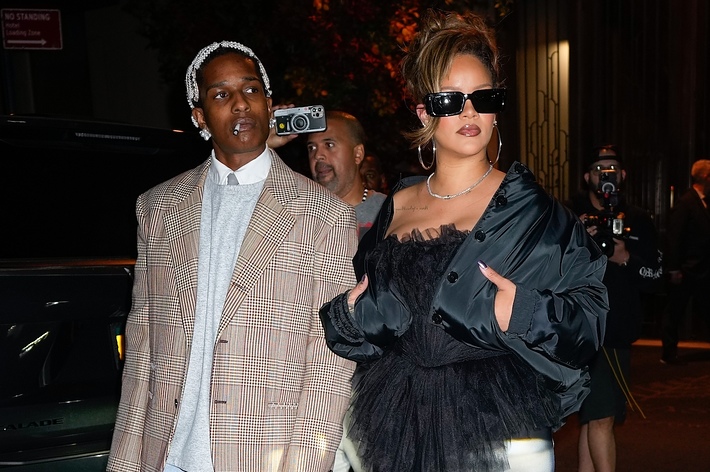 A$AP Rocky and Rihanna walking together, A$AP in a striped suit, Rihanna in a ruffled black dress