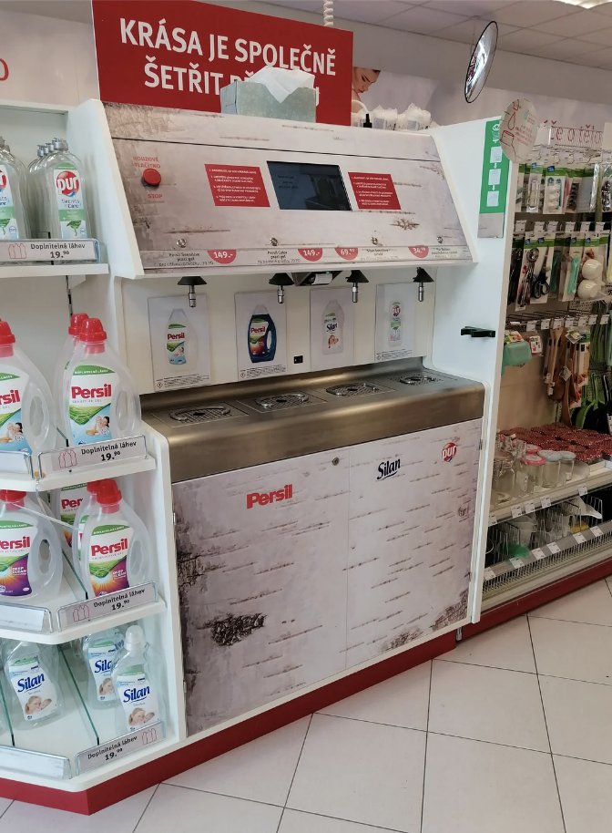 Self-service laundry detergent station with Persil products and signage in a store