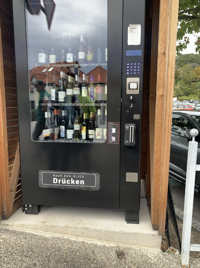 Wine vending machine outside with a selection of bottles, &quot;Nach dem Klick Drücken&quot; written on the bottom