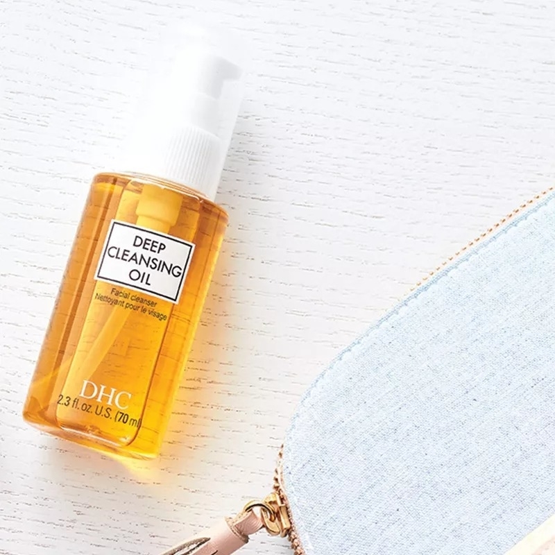 bottle of DHC Deep Cleansing Oil next to a cosmetic bag