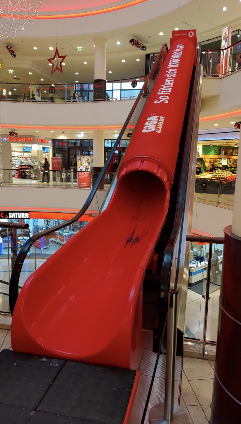 A large red indoor slide with a sign that says &quot;MAGIC SLIDE&quot; at a shopping mall