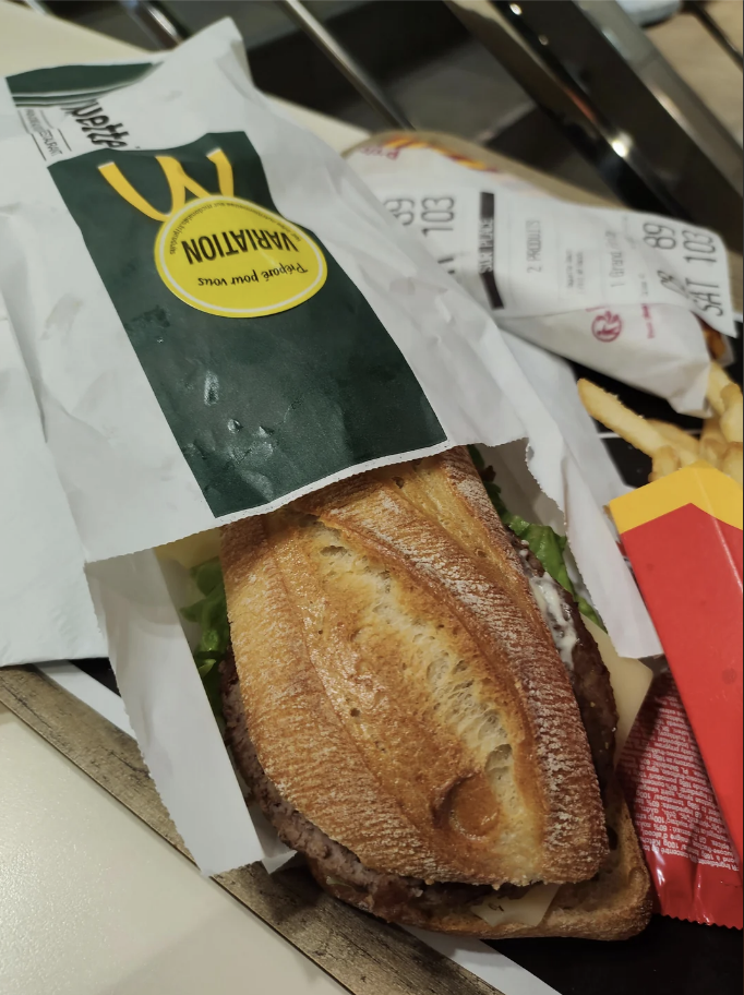 McDonald&#x27;s bag with logo, steak sandwich in a tray, and fries on the side