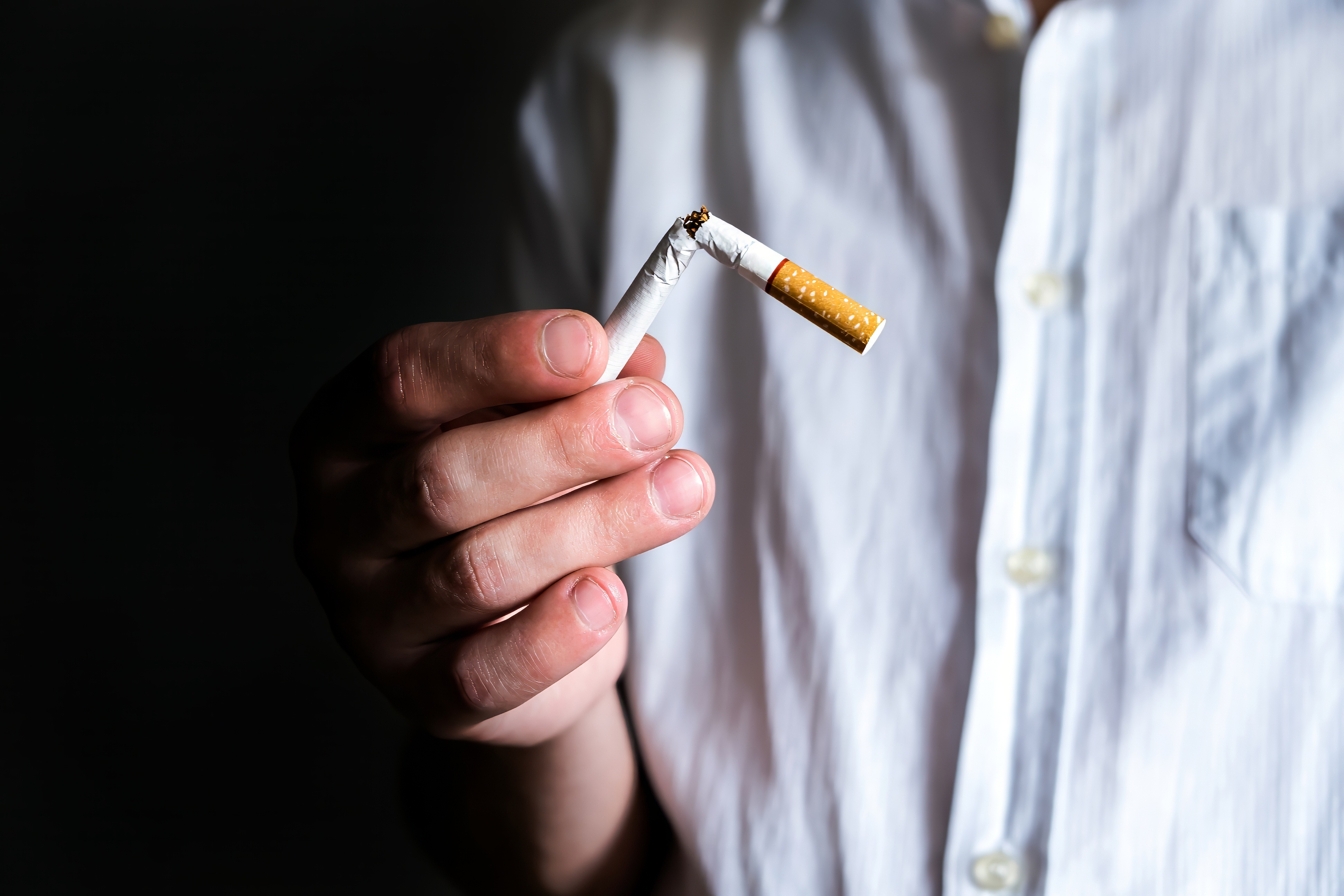 Person holding a broken cigarette, promoting quitting smoking