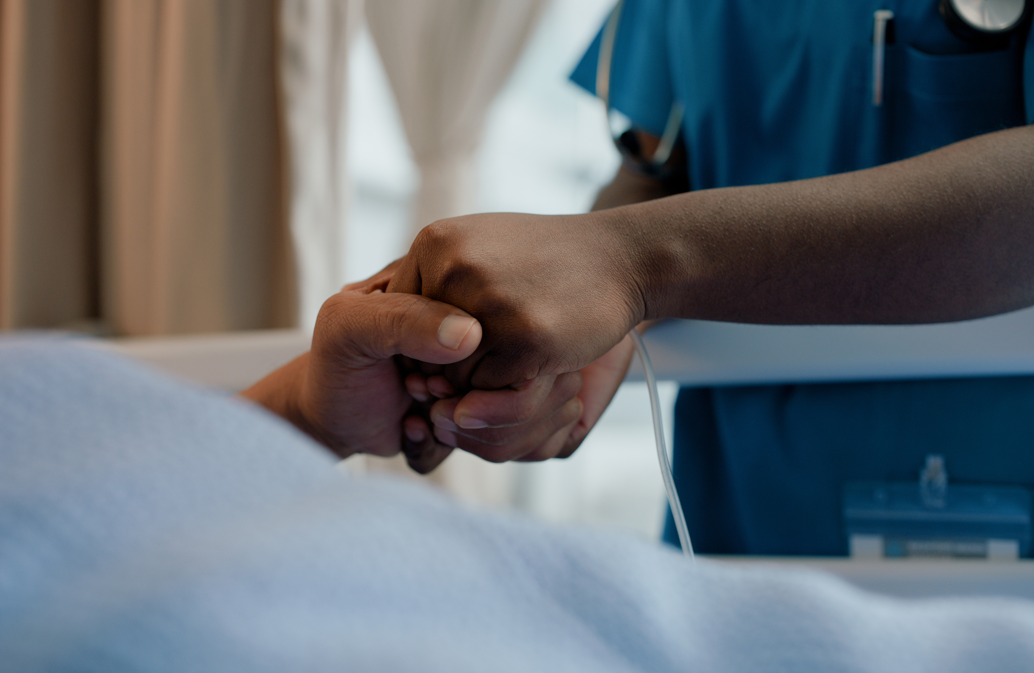 A healthcare worker holding a patient&#x27;s hand, offering comfort and support
