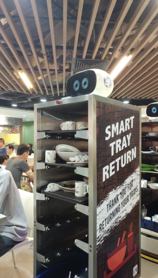 Smart tray return station with a &quot;Thank You for Returning Your Tray&quot; sign in a busy food court