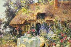 Painting of a quaint thatched cottage with a table set for tea in a flower-filled garden. No people present