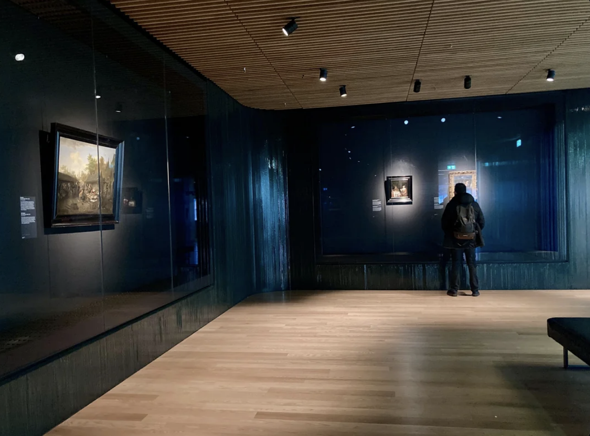 Person observing artwork in a dimly lit gallery
