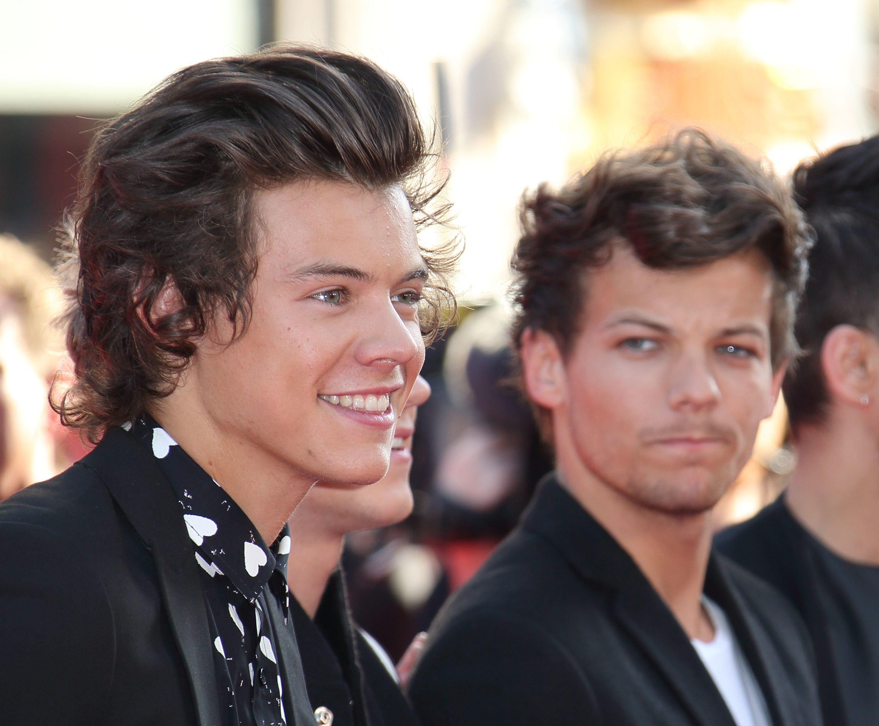 Harry Styles and Louis Tomlinson on the red carpet, Styles in a patterned shirt with a blazer, Tomlinson in plain tee and blazer