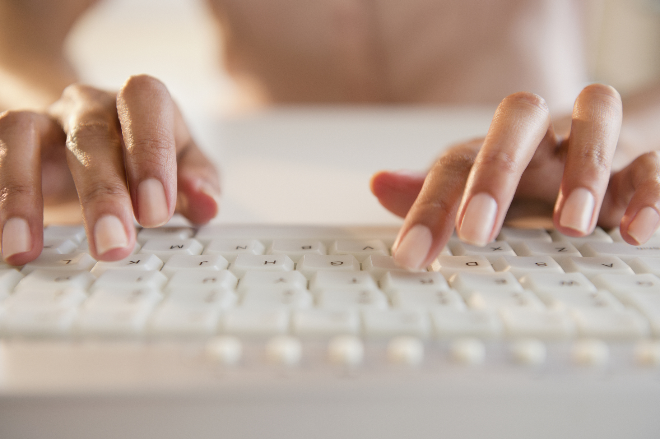 Person&#x27;s hands typing on a keyboard, close-up view, focusing on the activity of typing
