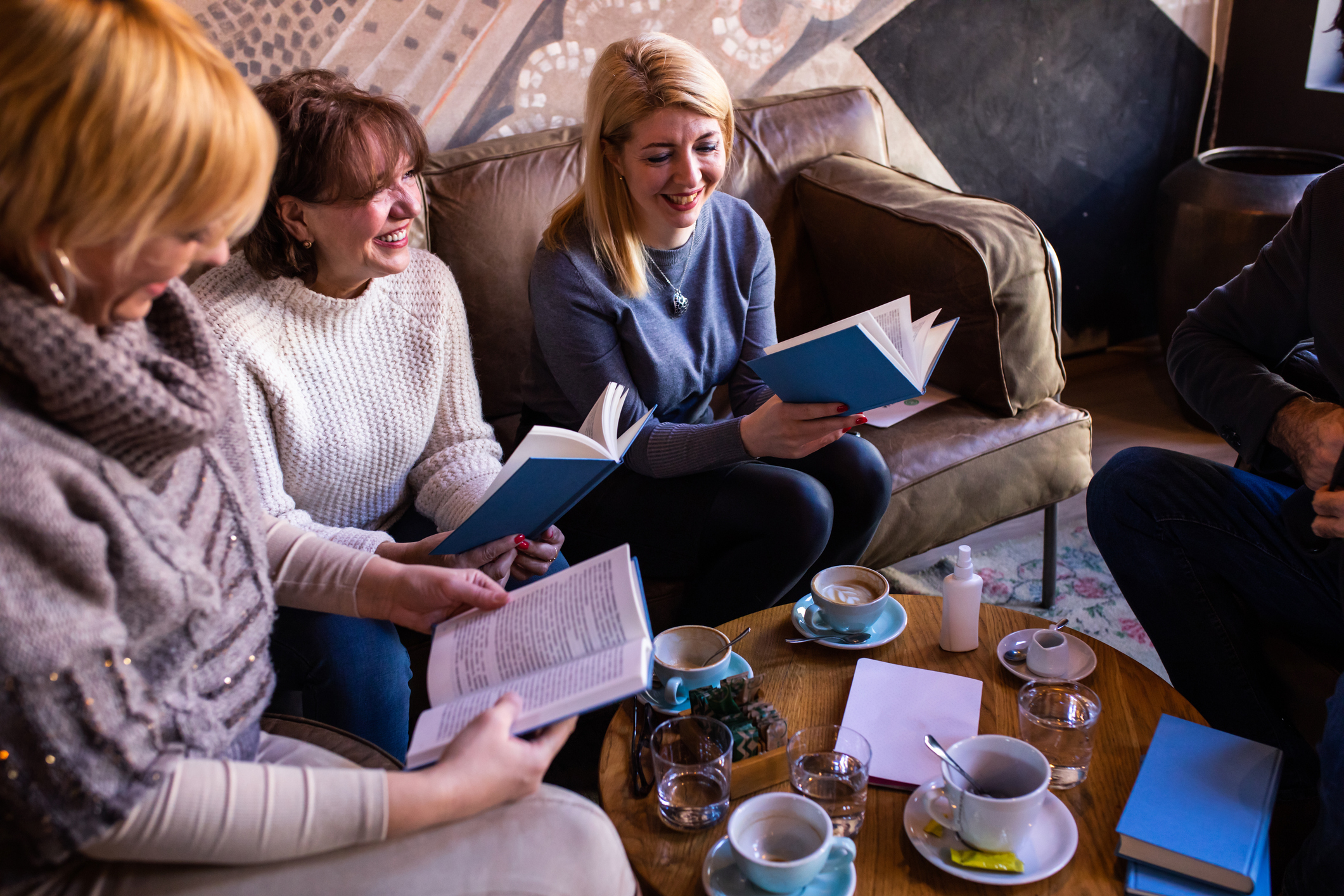 Group of friends enjoying a book club discussion in a cozy living room setting