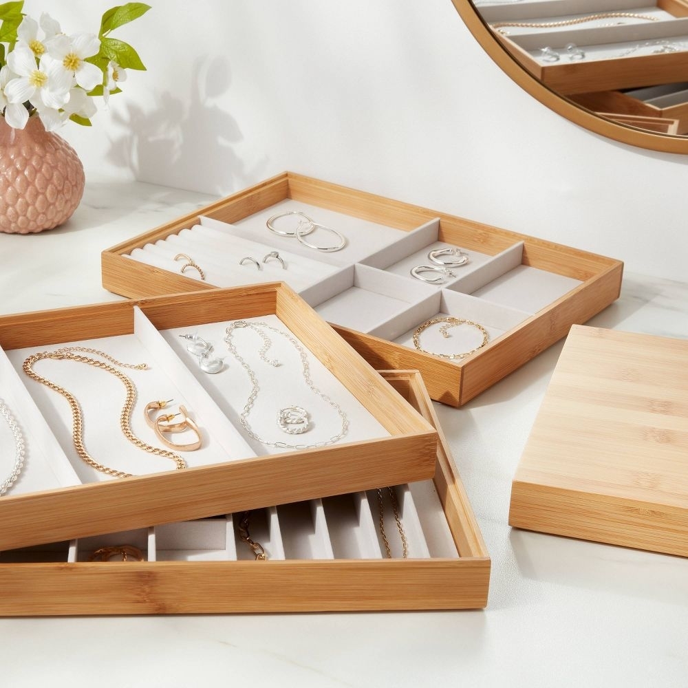 A wooden jewelry organizer with various compartments displaying necklaces and earrings