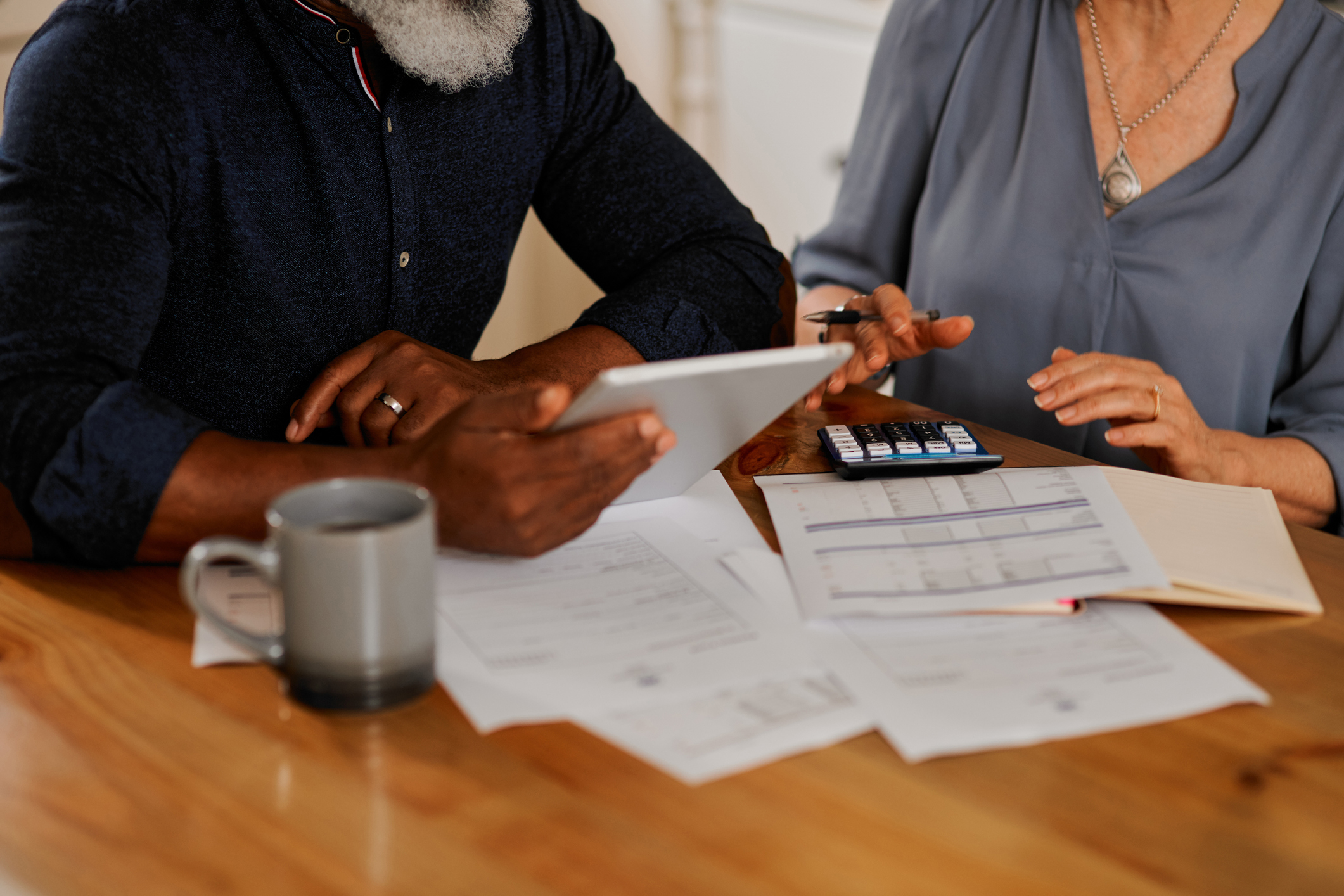 Two people reviewing finances with calculator and documents on a table