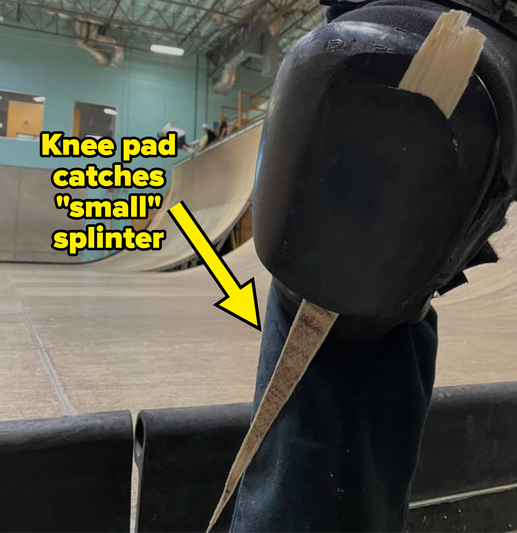 Person with skateboard at indoor skatepark, ramp in background, focus on knee pad