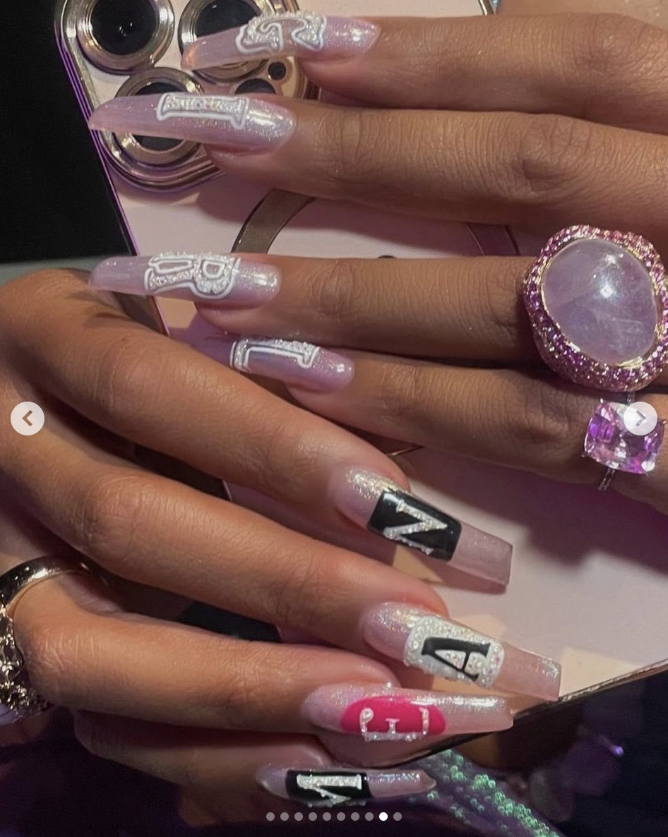 Close-up of intricately designed long nails with embedded jewels and various patterns