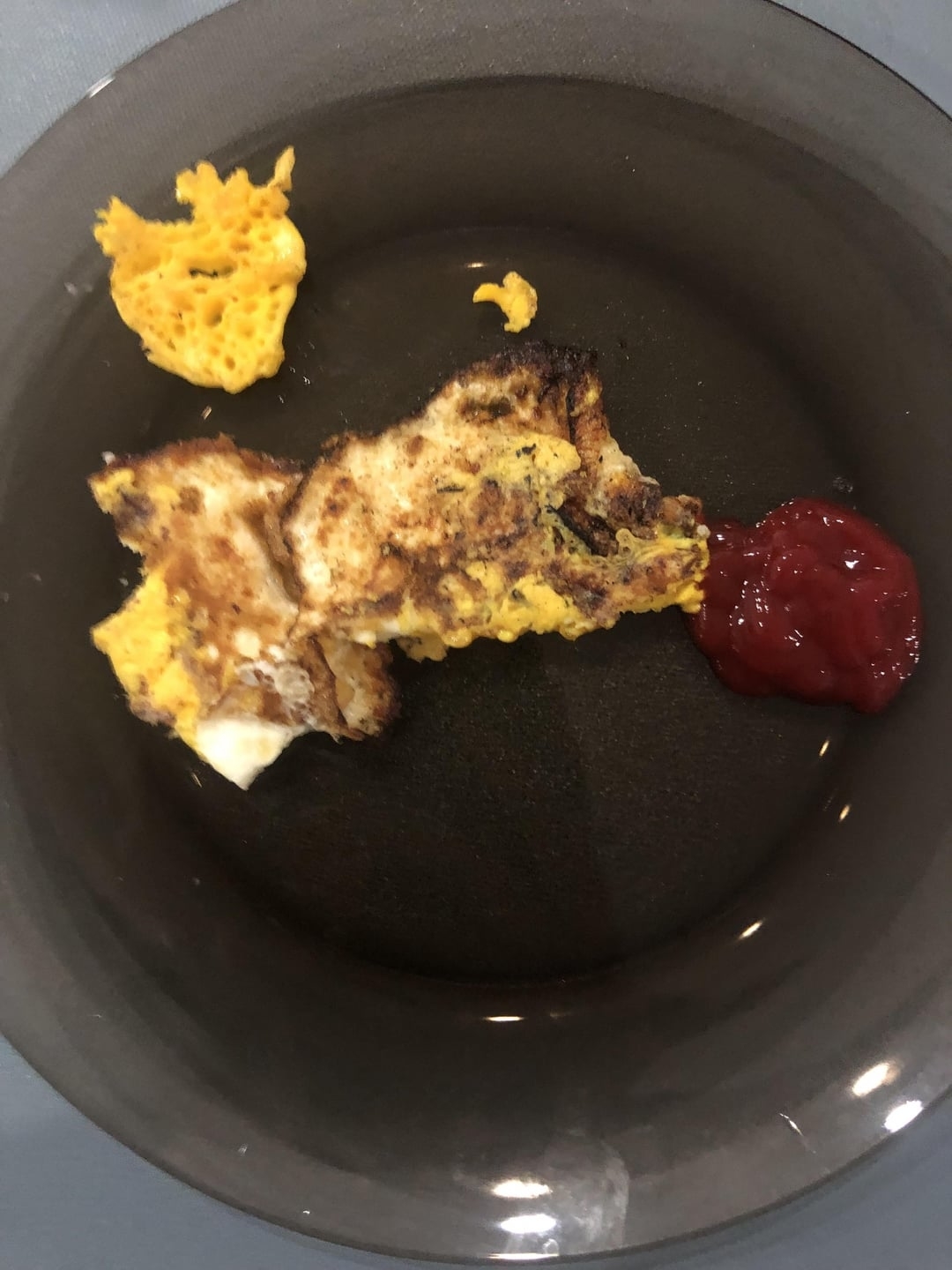 Burnt scrambled eggs with a side of ketchup on a plate