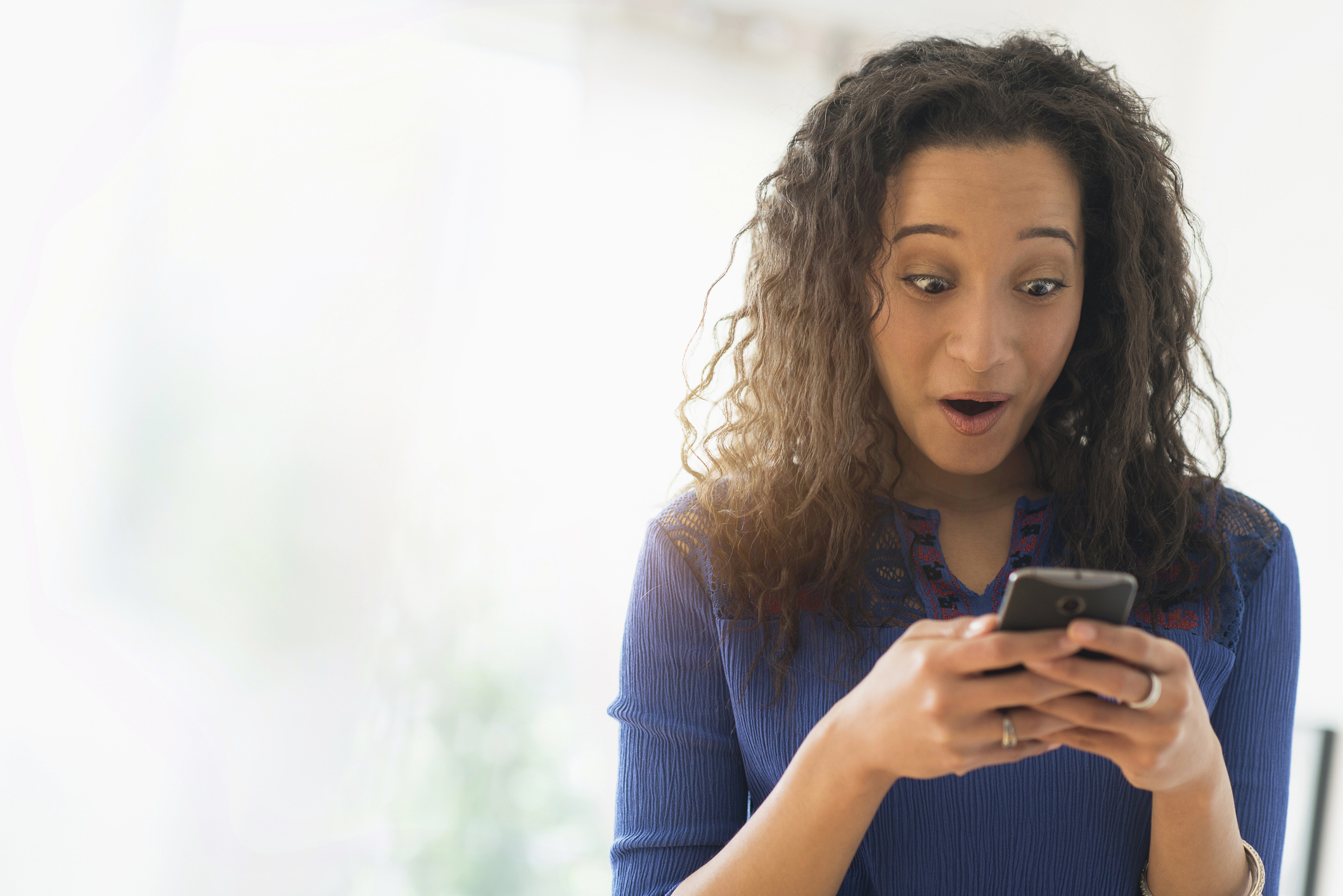 Woman looks at phone with surprised expression, possibly receiving unexpected romantic message