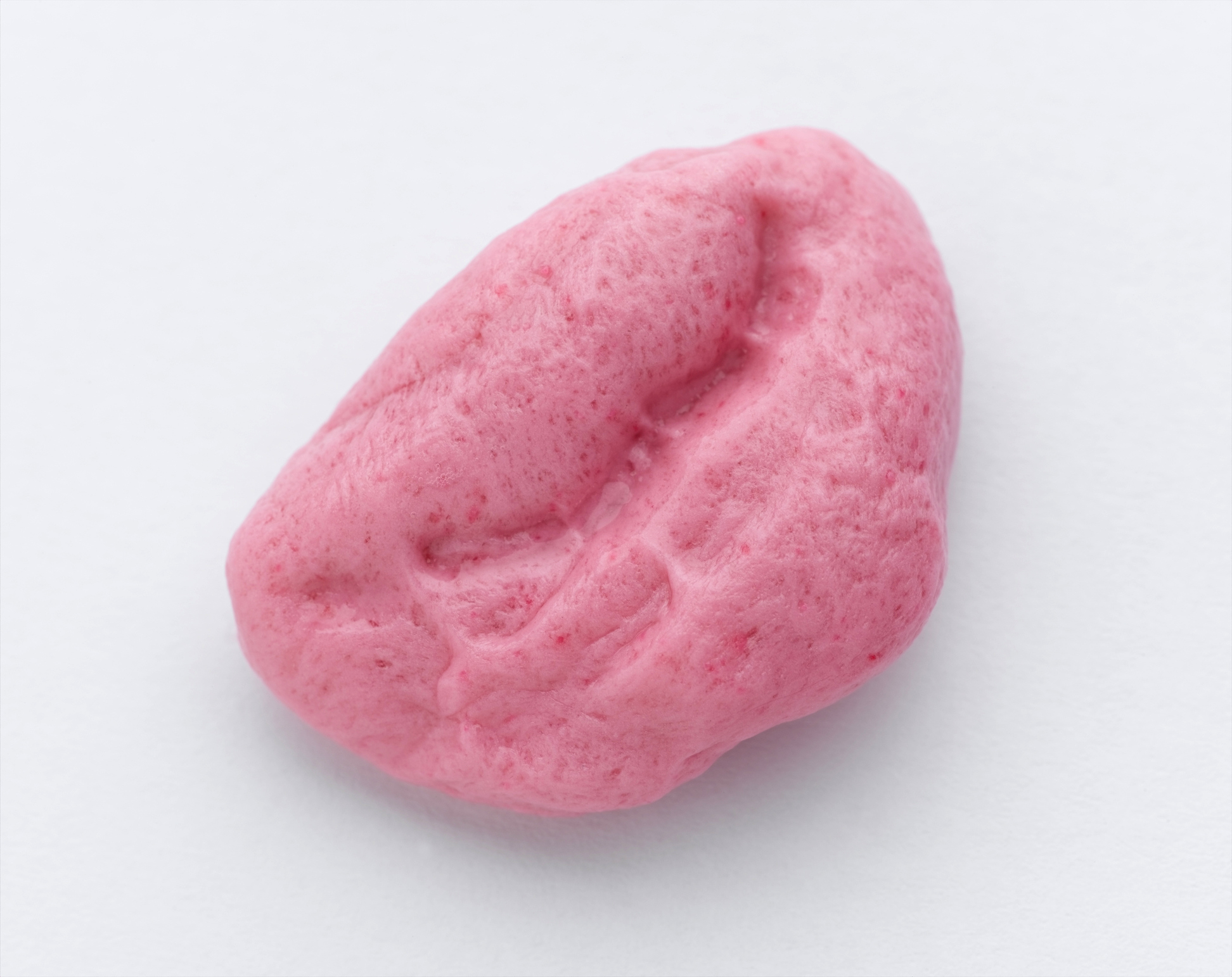 A pink, chewed bubble gum piece against a white background