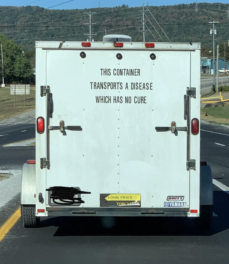 Truck with a sign reading &quot;This container transports a disease which has no cure&quot; and urging to &quot;look twice&quot; for motorcycles