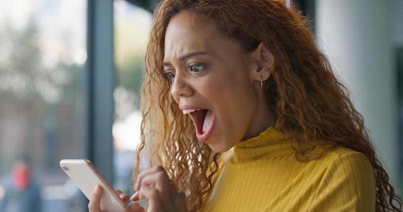 Woman expressing shock while looking at her phone, possibly receiving surprising messages