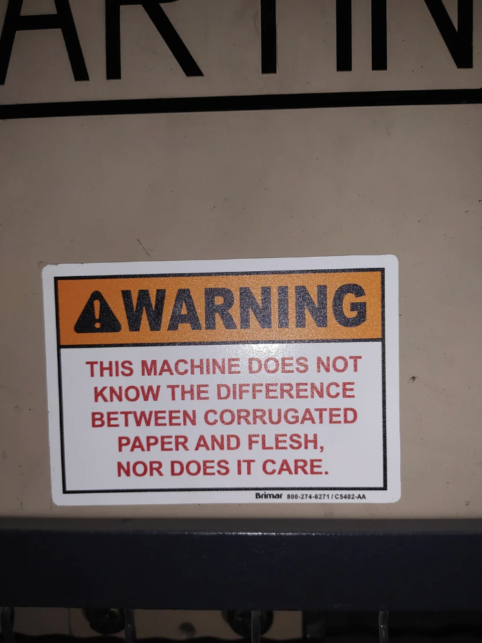 Warning sign on machinery cautioning that it cannot distinguish between materials and human flesh