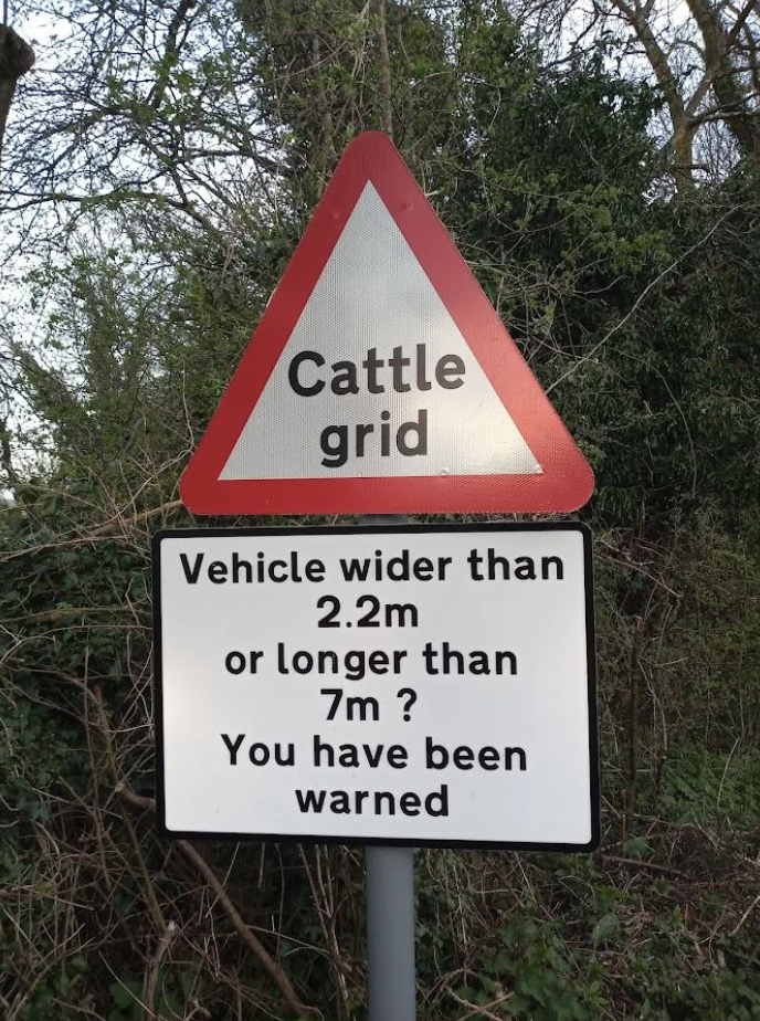 Traffic sign warning about a cattle grid for vehicles wider than 2.2m or longer than 7m, with a cautionary message below