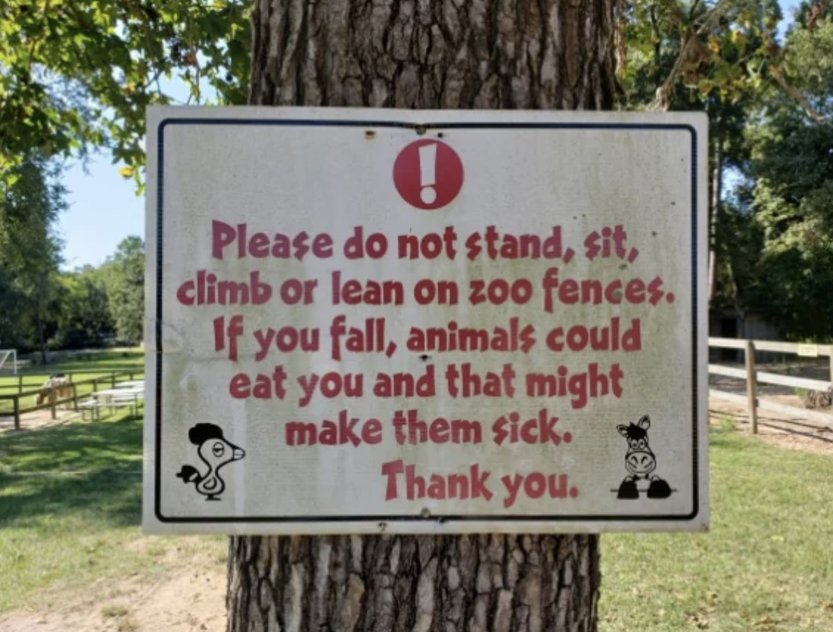 Sign warning not to stand, climb, or lean on zoo fences to prevent harm to oneself and animals