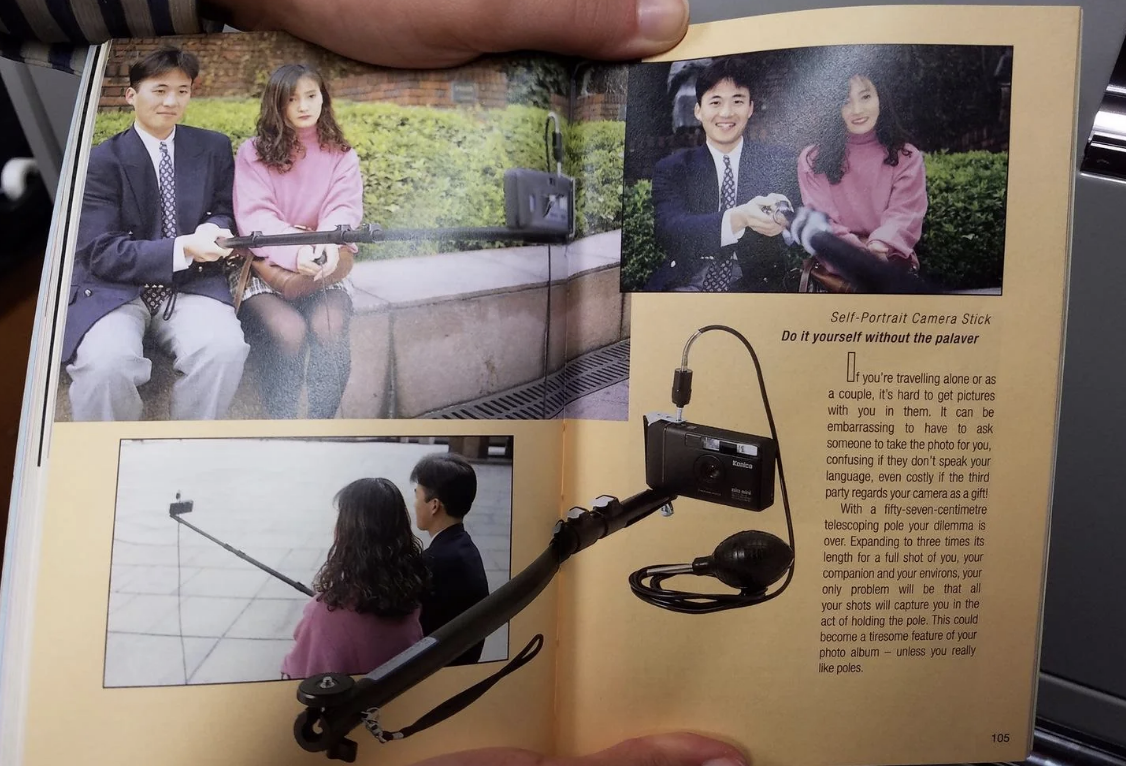Page of a magazine showing a couple taking a selfie with a camera stick and a product description below