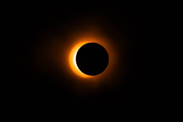 Total solar eclipse with corona visible, set against dark sky