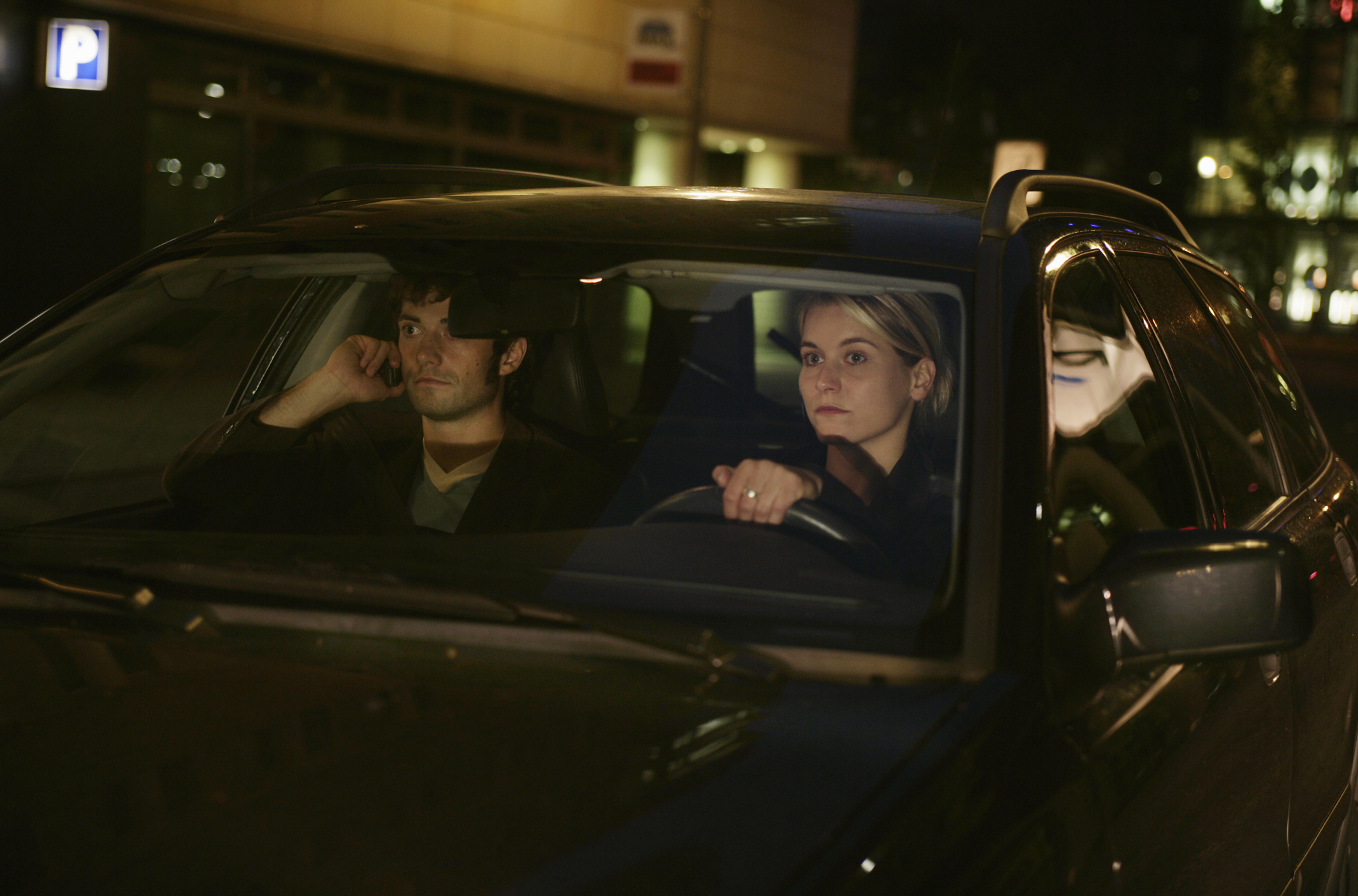 Two people sitting in a car, appearing to have a serious conversation