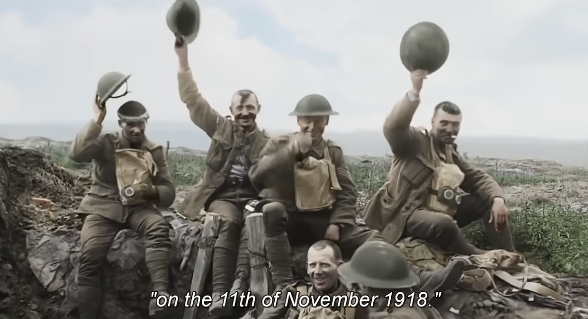 Five soldiers celebrating, waving hats, caption reads &quot;on the 11th of November 1918.&quot;