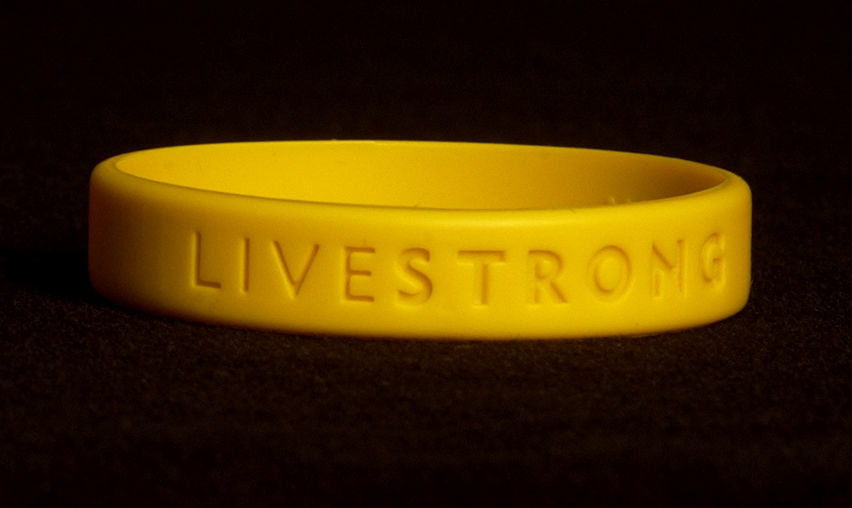 Yellow Livestrong wristband on a dark background