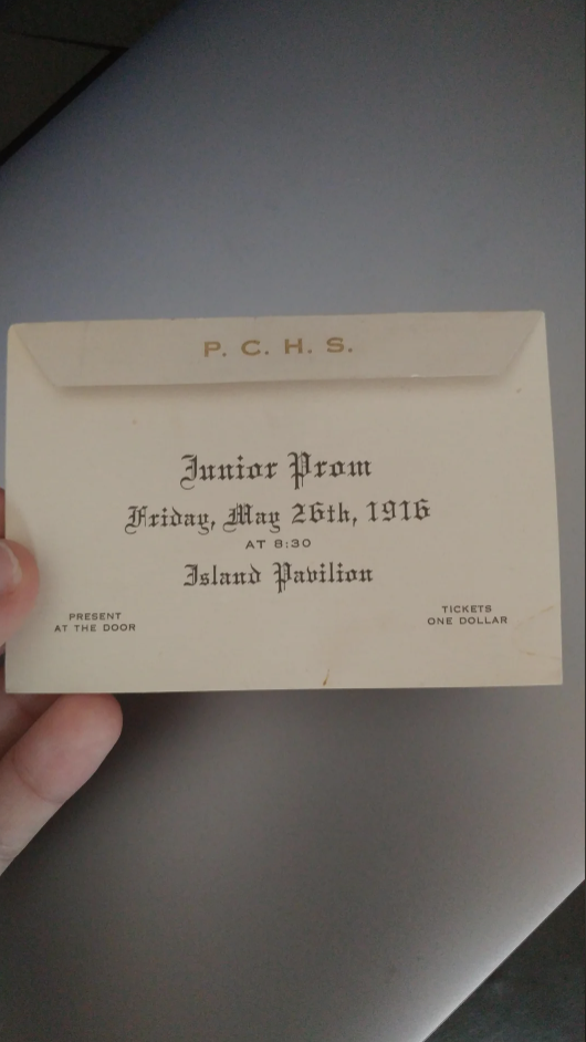 Hand holding a vintage invitation to P.C.H.S. Junior Prom at Island Pavilion on May 26, 1916