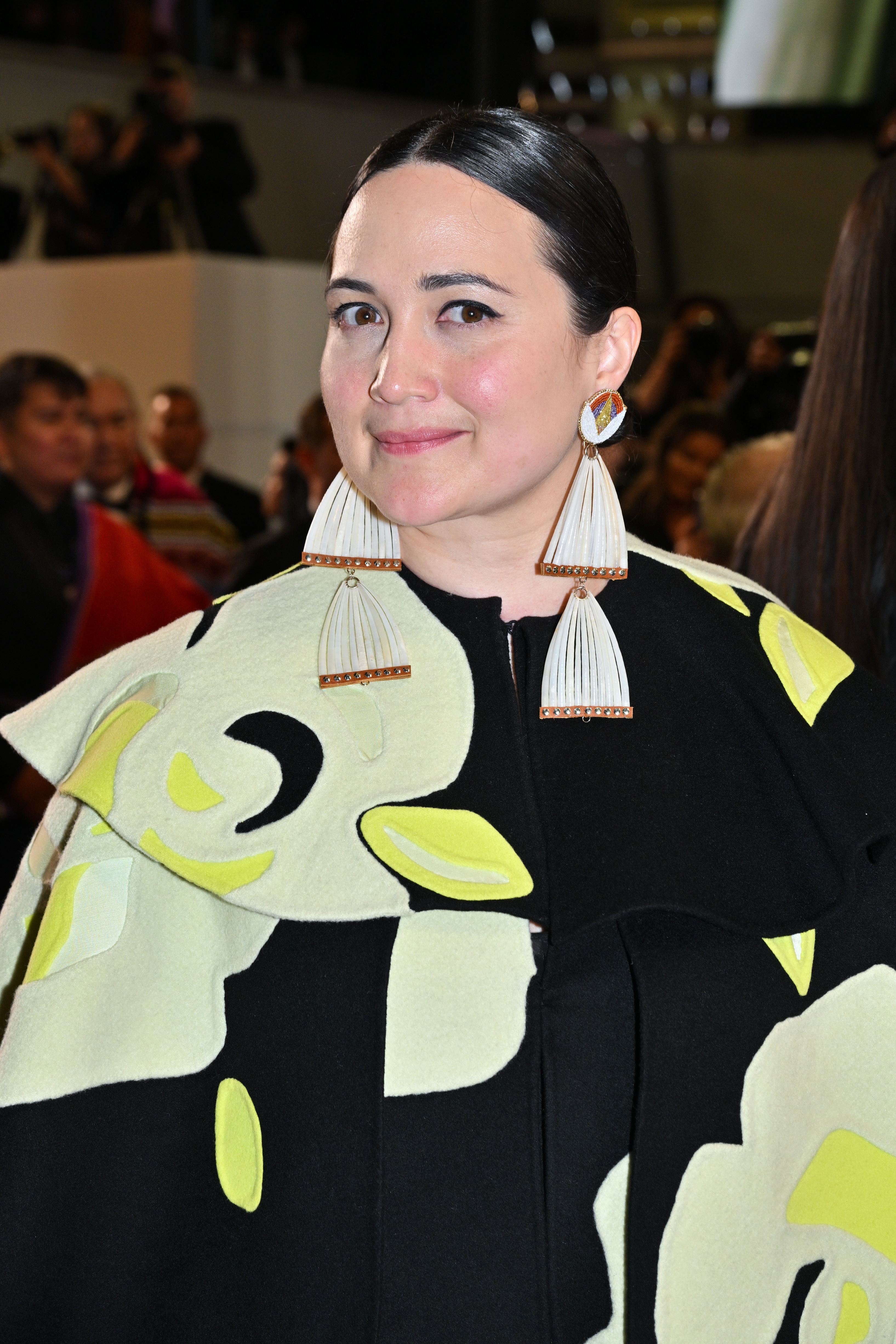 Woman at event wearing a blazer with abstract design, paired with large tassel earrings
